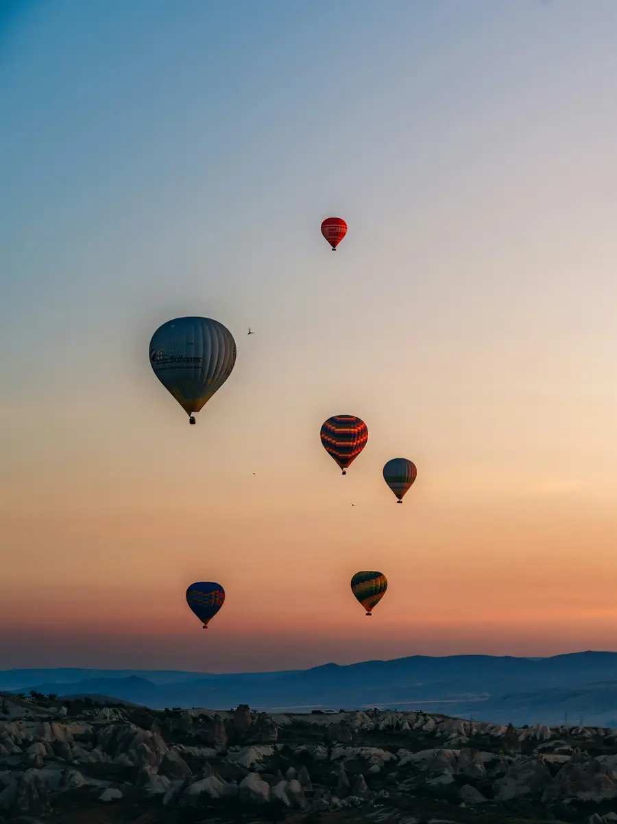 Balloons rising into a peach-coloured dawn